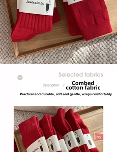 Close-up of red combed cotton crew socks with festive tags and brand paper packaging