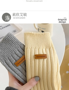 Detail of ribbed knit crew socks with brown leather brand labels in grey and beige