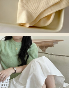 Detail of light green ribbed knit texture with gold necklace and leather watch