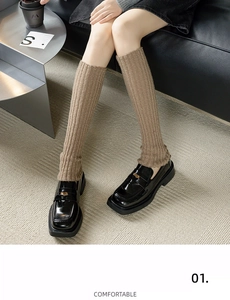 Détail de jambières en maille côtelée beige avec des mocassins en cuir verni noir