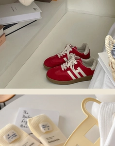Detail view of light yellow ribbed knit socks with a fabric label and retro red sneakers