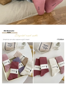 Macro shot of ribbed cotton slouch socks in assorted colors with branded paper labels