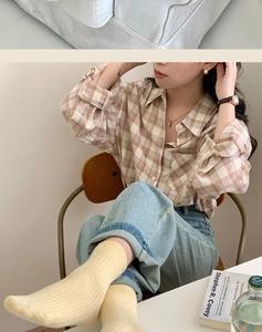 Close-up of a casual outfit featuring a retro brown plaid cotton-linen shirt and light jeans