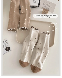 Close-up of thermal wool socks with ruffle edges and polka dots in warm earth tones