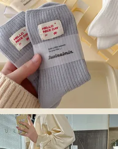 Detail of grey ribbed knit socks with white Hello Nice Day textile label and packaging