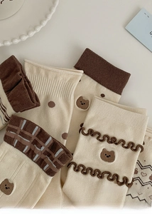 Détail de chaussettes en coton crème et café avec broderie ours et motifs à pois