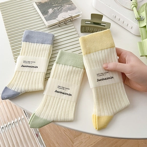 Three pairs of striped crew socks in blue, green, and yellow colorblock patterns