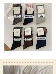 Flat lay of six pairs of striped cotton crew socks with buttons and white packaging