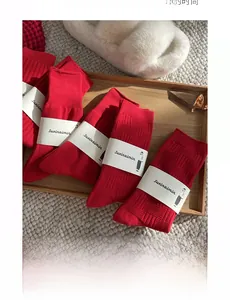 Red cotton socks in solid and checkered patterns displayed in a wooden tray
