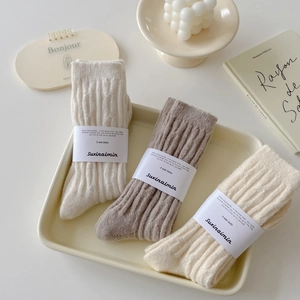 Three pairs of thick cable knit winter socks in beige and brown for a cozy home look