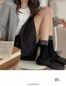 Detail of grey ribbed contrast socks with metal button accent and black strap shoes