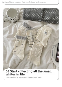 Detail of cream Japanese style mid-calf socks with cherry and star embroidery patterns