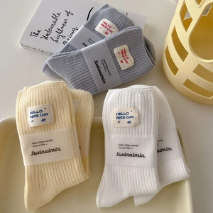 Three pairs of ribbed cotton mid-calf socks in grey, beige and white with text labels