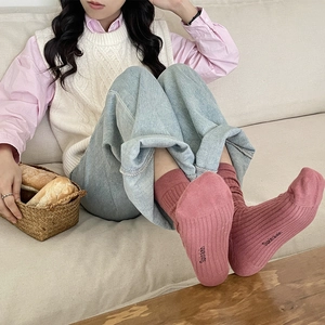 Women's pink ribbed cotton mid-calf socks shown in a cozy home lifestyle setting