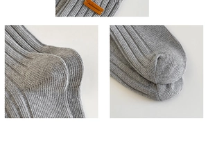 Detail of grey ribbed knit cotton socks featuring a brown leather brand label and stitching