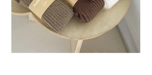 Détail de jambières en tricot avec texture côtelée en tons terre et étiquette