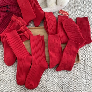 Red cotton crew socks set for New Year with various knit patterns on a wooden tray