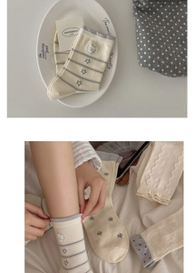 Close-up of cream cotton socks with cat star embroidery and striped rib details