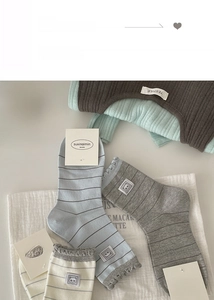 Flat lay detail of striped knit socks with panda patches in gray, blue and beige colors
