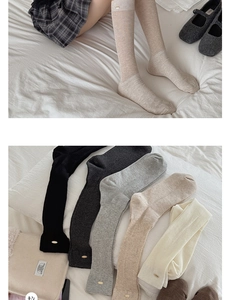 Détail de chaussettes en maille côtelée avec boucles dorées et tons naturels variés