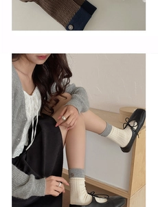 Detail of grey ribbed cotton socks with decorative button paired with black ballet flats