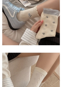 Detail of cream cotton socks featuring delicate cherry embroidery and wave-shaped cuffs