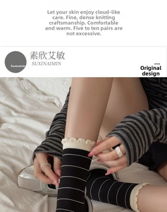 Detail of knitted mid-calf socks featuring black stripes and cream ruffled edge cuffs