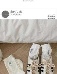 Detail of white cotton socks with cute blue bear embroidery and ruffle trim cuff