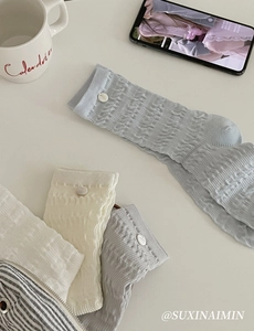 Detail view of slouch socks with decorative buttons in blue, white, and grey colors