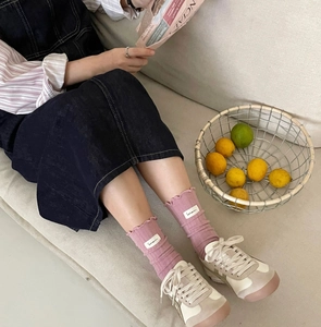 Chic mauve cotton crew socks with ruffle cuffs and decorative cloth label in home setting