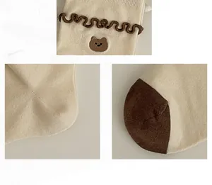 Détails de chaussettes crème avec bords ondulés marrons et broderie d'ours mignonne