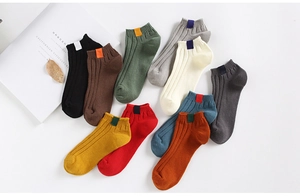 Detail of ribbed knit ankle socks with woven labels in 10 solid colors on white background
