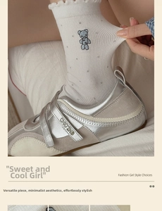 Detail of white knit sock with blue bear embroidery paired with silver velcro sneakers