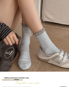 Detail of light blue cotton socks with grey stripes and ruffled cuffs in home setting