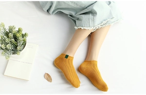 Detailed macro view of ginger yellow cotton rib-knit ankle sock with green fabric label
