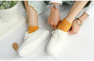 Detail of white litchi leather shoes with thick non-slip soles and yellow ribbed cotton socks