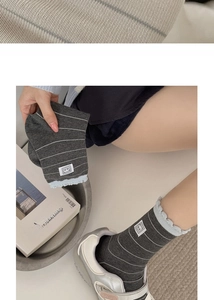 Close-up of dark grey striped crew socks with panda patch and ruffle cuff details