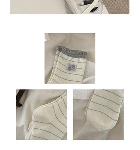 Close-up of cream striped socks with grey ruffled edges and a cute bear patch detail