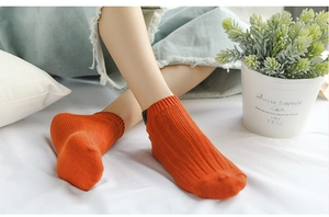 Detail of ribbed knit orange ankle socks with black label on comfortable home background