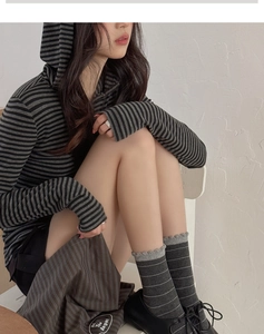 Close-up of ruffled cuff detail on grey striped crew socks with classic black oxfords