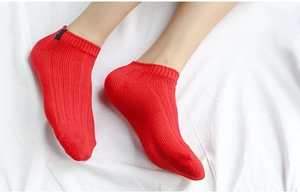 Detailed close-up of vibrant red low-cut cotton socks with ribbed texture on model