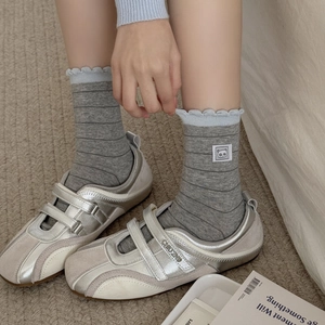 Grey striped crew socks with panda patch and ruffle trim worn with silver sneakers