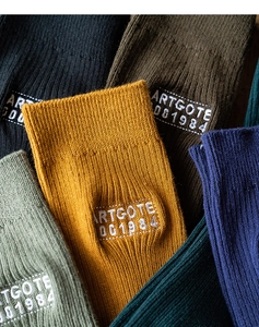 Close-up of ribbed knit cotton crew socks featuring retro earth tones and lettered tags