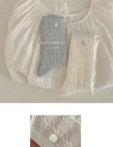 Detail of knit socks with wavy texture and button accents in blue and cream tones