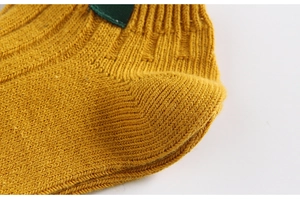 Macro shot of yellow knitted socks heel with detailed stitching and green fabric label