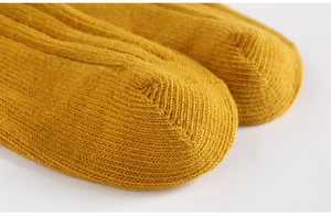 Detailed macro view of the seamless toe stitching on solid ginger yellow cotton knit socks