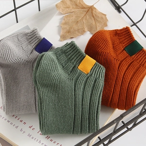 Three pairs of ribbed knit ankle socks in grey, green, and orange with small side labels