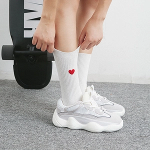 Chaussettes blanches avec cœur rouge brodé portées avec des baskets style sport