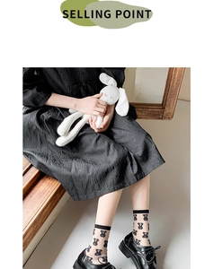 Detail of sheer black crew socks featuring cute bear patterns with dress and shoes