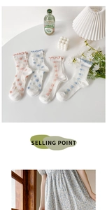 Detailed view of floral embroidery and retro ruffled edges on white cotton socks